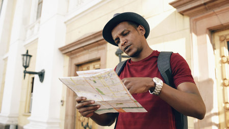 African american tourist man looking into paper city map exploring sightseeings during travelling in...