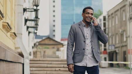 Mixed race businessman talking at smartphone and feels happy about making deal outdoorsの写真素材