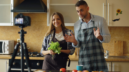 Young attractive couple shooting video food blog about cooking on dslr camera in the kitchenの写真素材