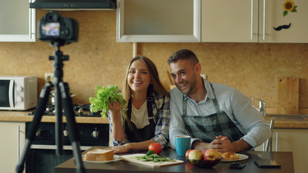 Young attractive couple shooting video food blog about cooking on dslr camera in the kitchenの写真素材