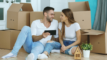 Young couple sitting on floor using tablet computer after reloction in their new homeの写真素材
