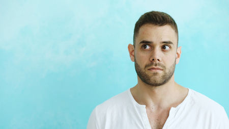 Portrait of young handsome man grimacing into camera and show different emotions on blue backgroundの写真素材