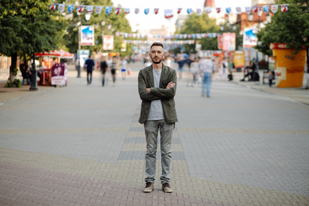 Young man standing still at sidewalk with people moving aroundの写真素材