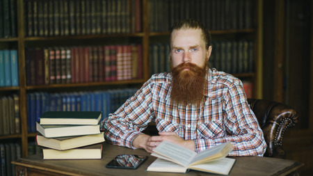 Portrait young bearded man in library and looking into cameraの写真素材