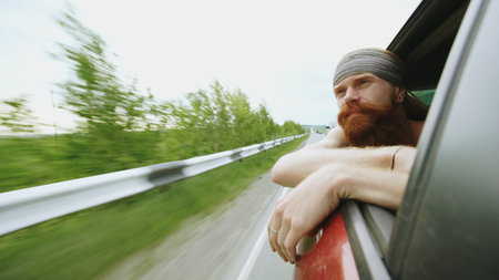 Happy young tourist man watching in car window relaxed while travelingの写真素材