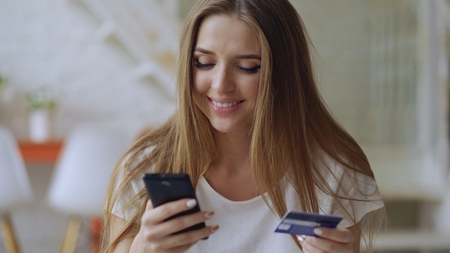 Beautiful young woman have online banking and shopping using smartphone and credit card at homeの写真素材