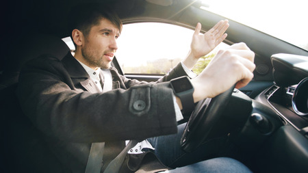 Young business man driving car very upset and stressed after hard failure and moving in traffic jamの写真素材