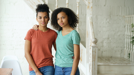 Portrait of two beautiful african american girlslooking into camera indoorsの写真素材