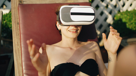 Young woman dressed in a glasses headset of virtual reality in hotel swimming poolの写真素材