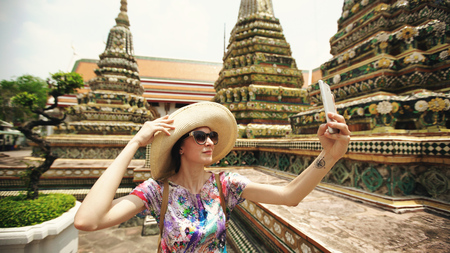 Young woman tourist taking selfie with smartphone at temple sightseeing in Bagnkok Thailand during travelingの写真素材