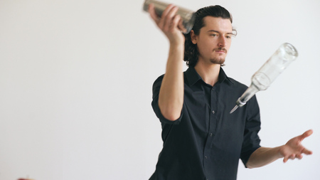 Professinal bartender man juggling bottles and shaking cocktail at mobile bar table on white backgroundの写真素材