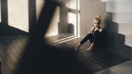 Closeup of young teenage girl dancer crying after loss perfomance sits on floor in hall indoorsの写真素材