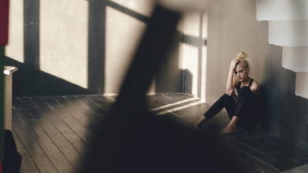 Young teenage girl dancer is suffering after loss casting sits on floor in dance studio indoorsの写真素材