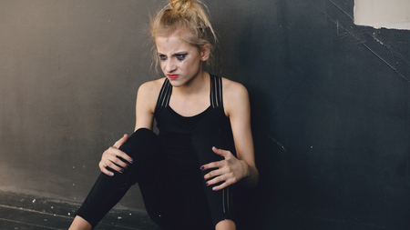 Young teenage girl dancer is very angry and suffering after loss casting sits on floor in dance studio indoorsの写真素材