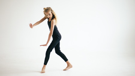 Modern beautiful teenage girl dancer dancing contemporary on white background indoorsの写真素材