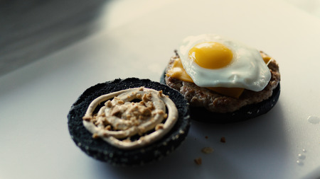 Closeup of grilled black burgerwith sauce and eggs on kitchen boardの写真素材