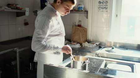 Professional chef man prepare gravy sauce with spices on oven at restaurant kitchenの写真素材