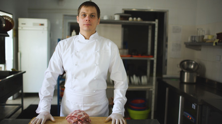 Professional chief cook posing before prepare steak dish at restaurantの写真素材