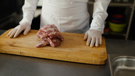 Closeup of professional chef prepare meat ribs on cutting board at restaurant kitchenの写真素材