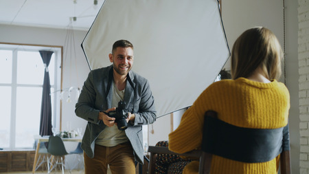 Professional photographer taking photos of model on digital camera working in photo studio