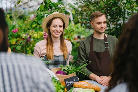 Smiling shop assistants friendly man and womn are selling organic food to customers in farm market enjoying work. People, occupation and farming concept.の写真素材