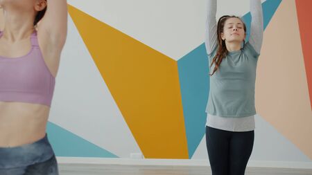 Modern youth male and females are exercising in yoga club wearing trendy clothing enjoying sports caring for health. Hobby, leisure and sportive people concept.の写真素材
