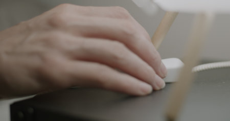 Close-up of female hand turning off light touching lamp switch on bedside table and sleeping at...