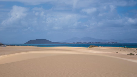 Bright light on the sand Park Natural with mountain backdrop in Corralejo, Fuerteventura, Canary...