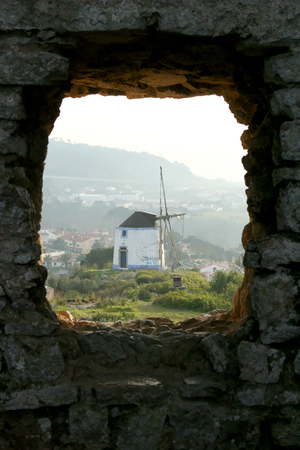 typical mill in the city of Obidos, Portugal, seen from a window of the castle in a foggy dayの写真素材