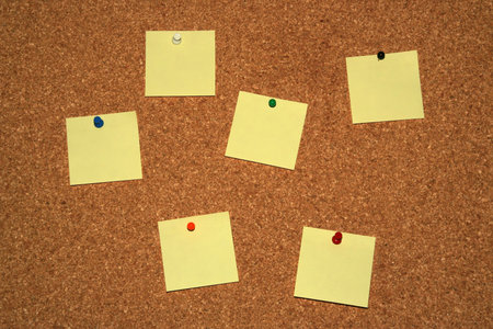 cork board with six empty yellow notes 