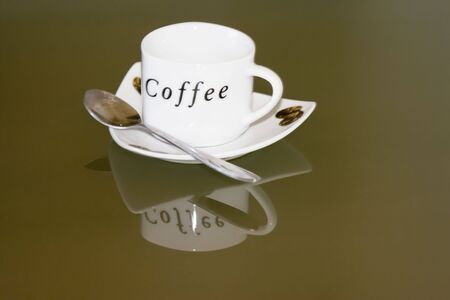 white cup of coffee an reflection in glass tableの写真素材