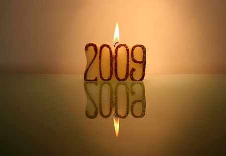 new year candle and reflection in glass tableの写真素材