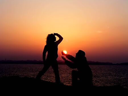 silhouette of couple at sunset near sea - love momentsの写真素材