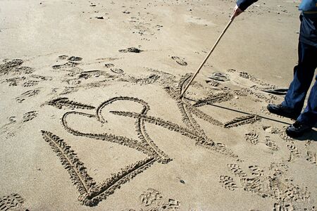 man drawing Love in the sand - valentine messageの写真素材