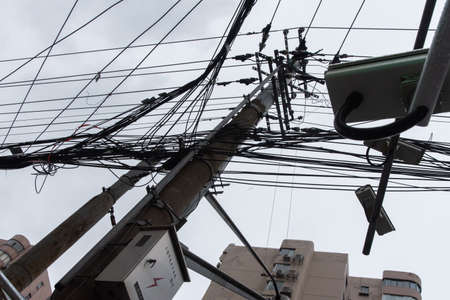 Shanghai, China - February, 2019. Messy tangle of electrical and telephone wires on the street pole.のeditorial素材