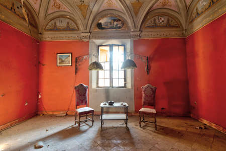 September 2021, Italy. Living room in an abandoned castle, with table, chairs and tea service. Urbexのeditorial素材