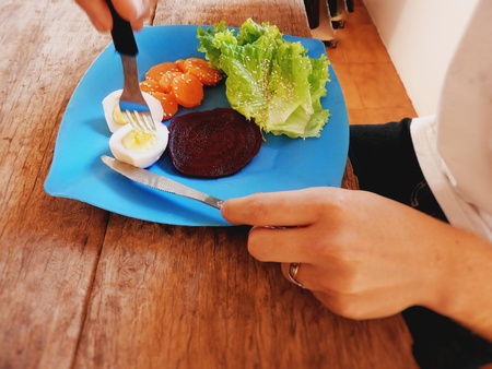 Young man cutting boiled eggs on the salad plate.の写真素材