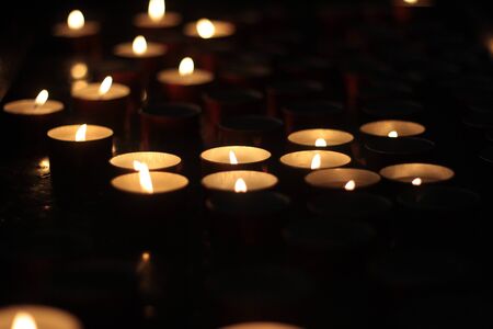 Votive candles glowing in the dark. close up. Religion and faith icon or background.の写真素材