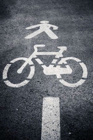 Pedestrian and cycle lane sign or symbol painted on asphalt. Black and white. Vertical shot.の写真素材