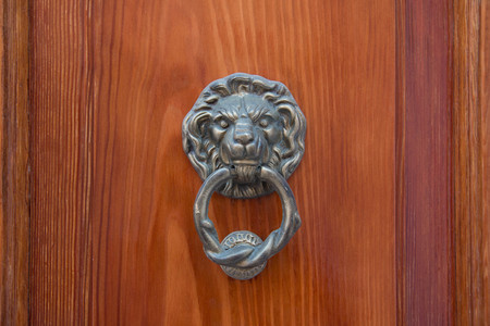 brass lion head with a large brass ring gripped in its mouth. detail of an italian wooden door.の写真素材