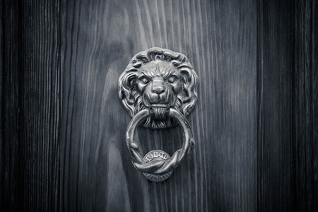 brass lion head with a large brass ring gripped in its mouth. detail of an italian wooden door.の写真素材