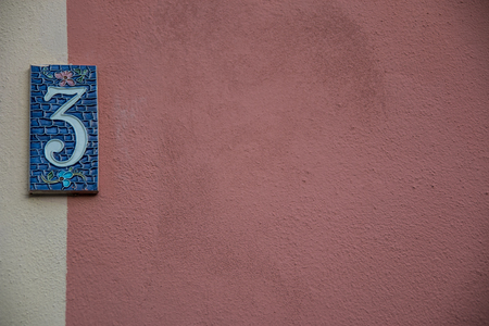Antique pink wall with blue "3" house number on the left side. Number three Background or wallpaper.の写真素材