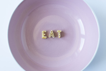 The word "eat" written with pasta in a pink dishの写真素材