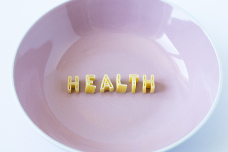 The word "health" written with pasta in a pink dishの写真素材