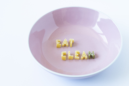 The word "eat clean" written with pasta in a pink dishの写真素材