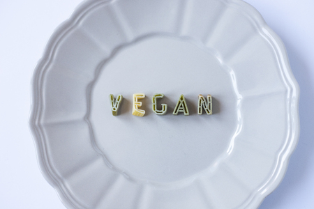 the word "vegan" written with pasta in a beige dishの写真素材