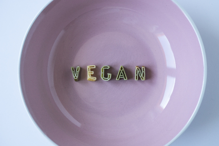 the word "vegan" written with pasta in a pink dishの写真素材