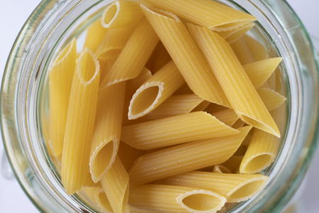 Top view of a circular glass jar containing raw pasta.の写真素材