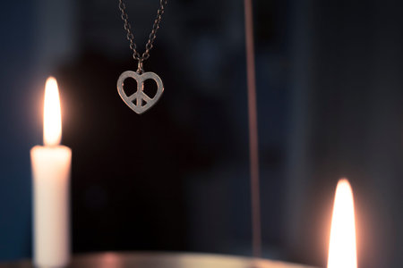 Peace, love, christmas  background with a peace heart symbol pendant hanging among candles glowing...