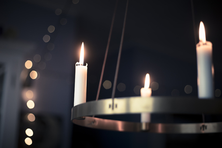 Winter, christmas or hygge background with candles glowing on a golden advent chandelier. Blue filter.の写真素材